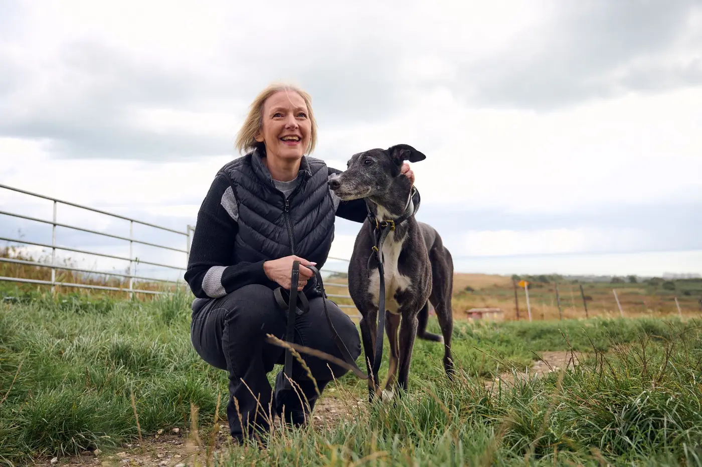 lady and greyhound in field